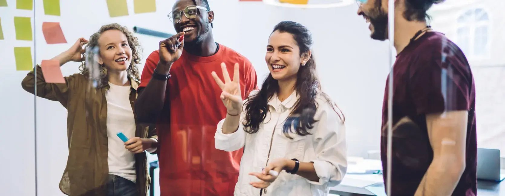 Mitarbeitende stehen vor einer Glaswand und sammeln Ideen