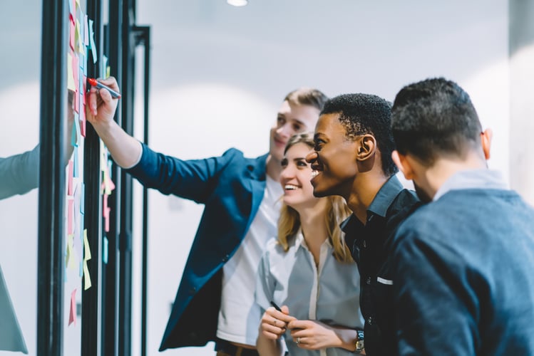 Personalstrategie: Fachkräfte stehe um ein Flipchart und erarbeiten gemeinsam etwas.