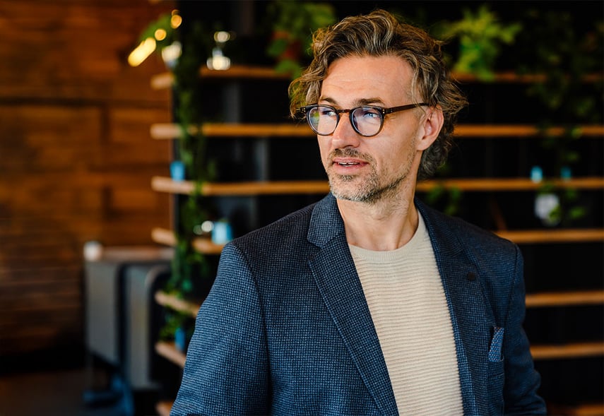 Erfahrener Manager der contec Unternehmensberatung, Gesundheits- und Sozialwirtschaft steht in einem warmen Büro und hält ein Tablet in der Hand.