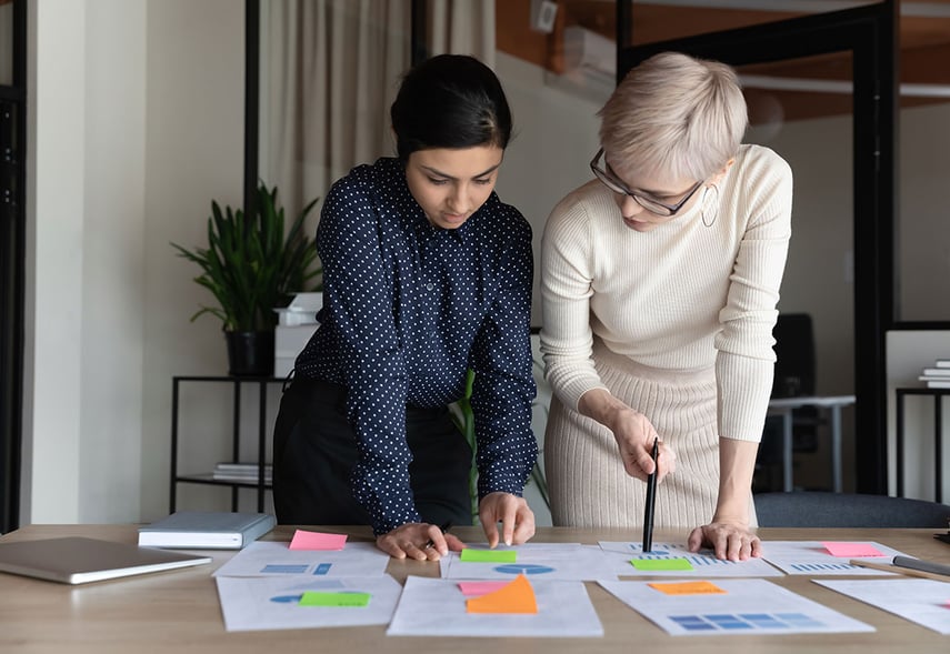 Zwei Beraterinnen der contec GmbH Unternehmensberatung und Personalberatung der Gesundheitswirtschaft und Sozialwirtschaft für den Fachbereich Komplexträger stehen am Schreibtisch und beraten gemeinsam über eine Ganzheitliche Beratung