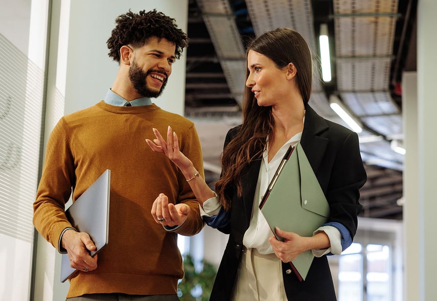 Zwei Kolleg:innen laufen nebeneinander im Büro und sprechen über den Change-Management Prozess