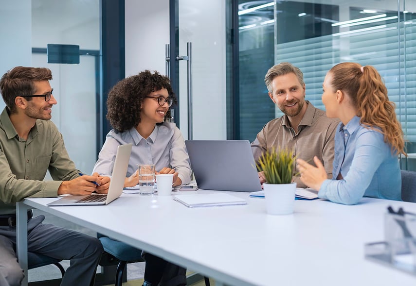 Vier Kolleg:innen sitzen an einem Tisch und diskutieren über den Zusammenhang von Change-Management und Kulturwandel