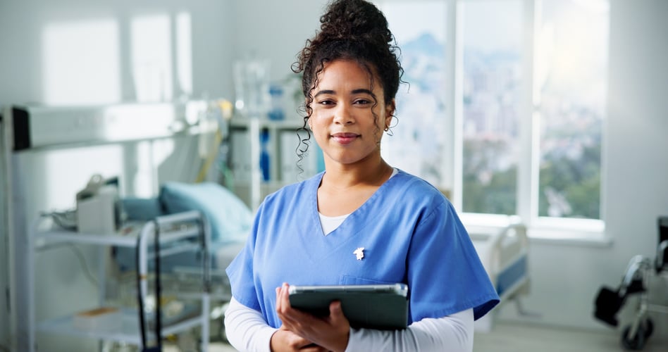 Eine junge Pflegerin im Krankenhaus hält ein Tablet in der Hand und schaut freundlich in die Kamera_Prozesse digitalisieren im Krankenhaus-conZepte