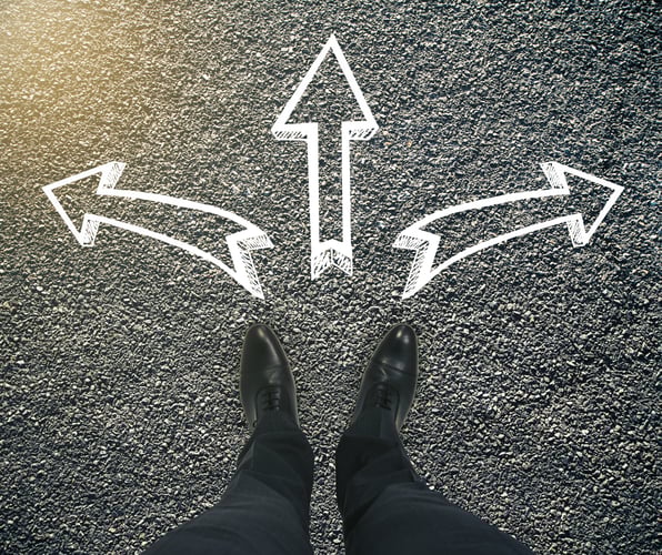 Paradoxie-Management: Ein Entscheider steht vor mehreren Richtungspfeilen und muss sich entscheiden.