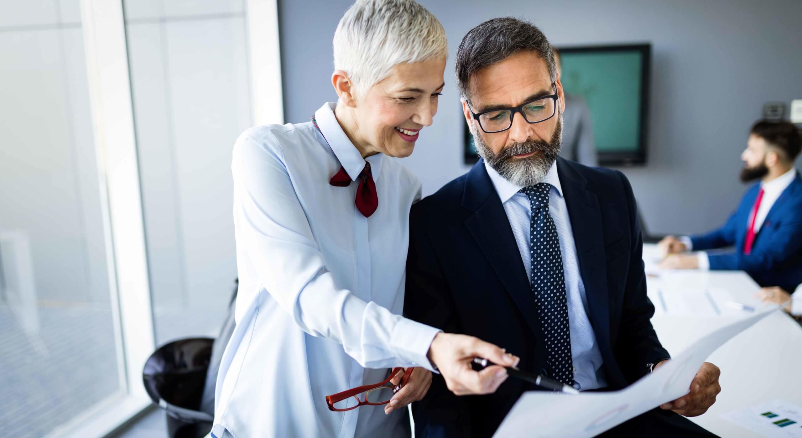 Zwei ältere Mitarbeitende planen gemeinsam das Executive Onboarding einer neuern Führungskraft.