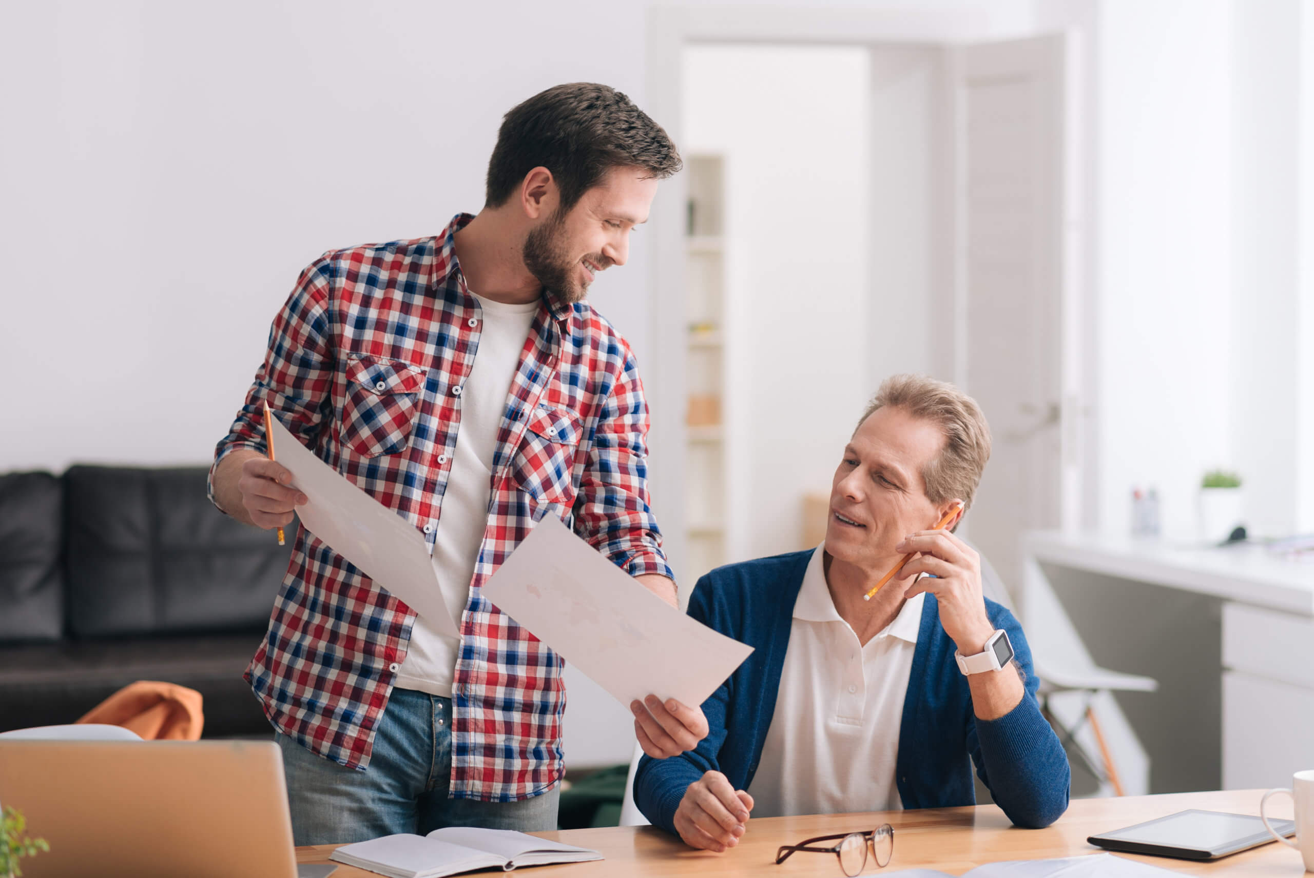 Ein junger und ein älterer Mitarbeiter arbeiten im Büro am Fachkonzept für für eine Werkstatt (WfbM)