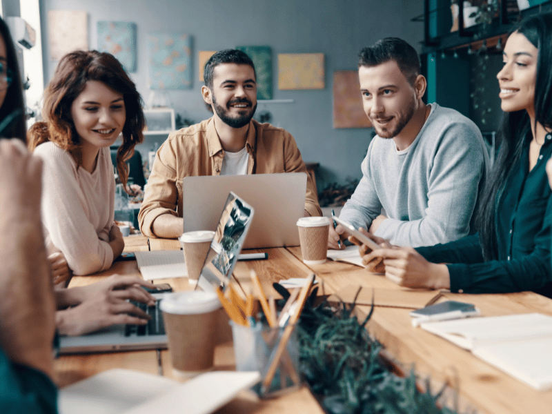 Zwei Mitarbeiterin und ein Mitarbeiter von contec sitzen an einem Konferenztisch und arbeiten an ihren Notebooks.