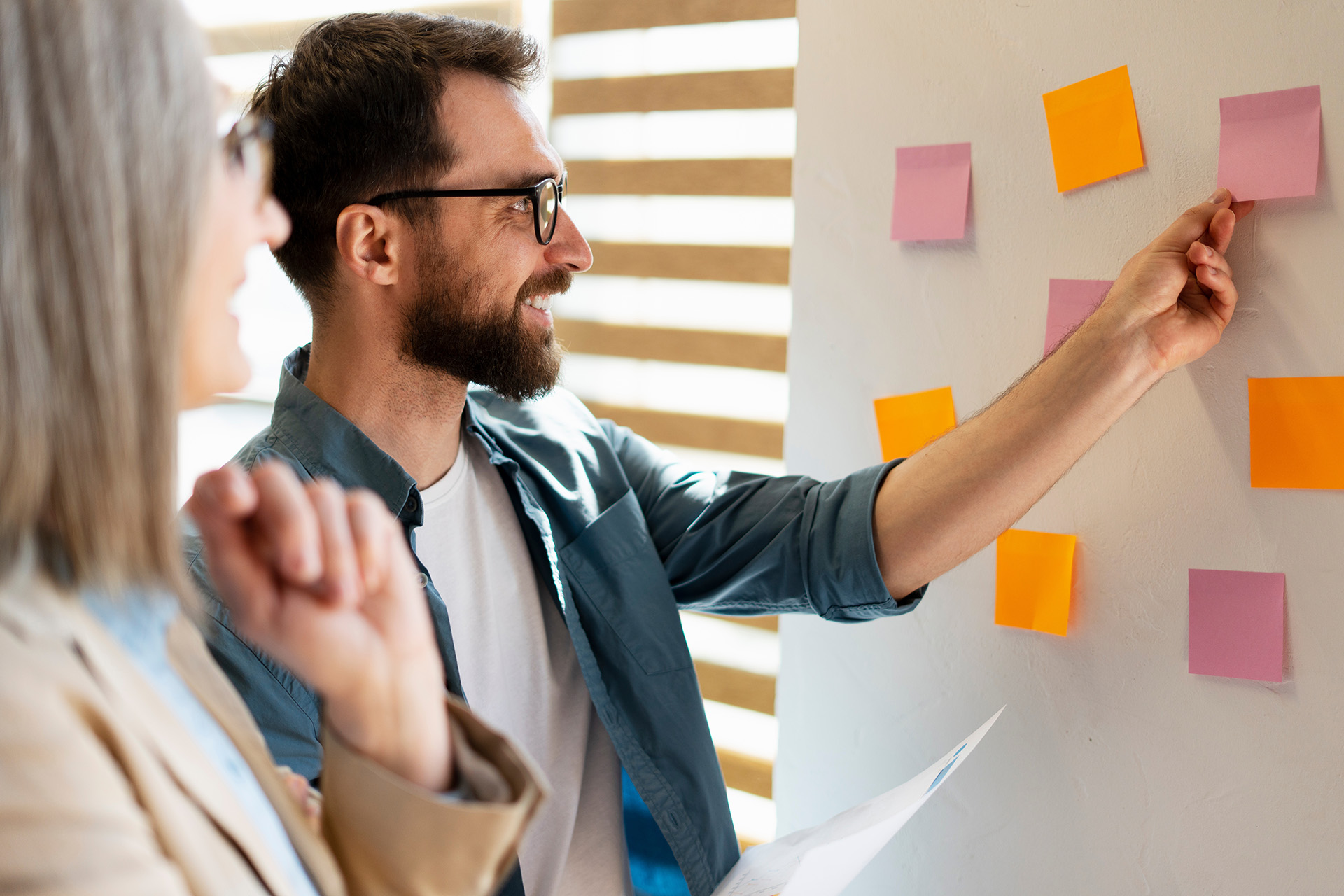 Eine Frau und ein Mann stehen vor einem Flipchart und arbeiten gemeinsam an der nötigen Personalsteuerung, um mit dem Fachkräftemangel in der Kinder- und Jugendhilfe umzugehen.