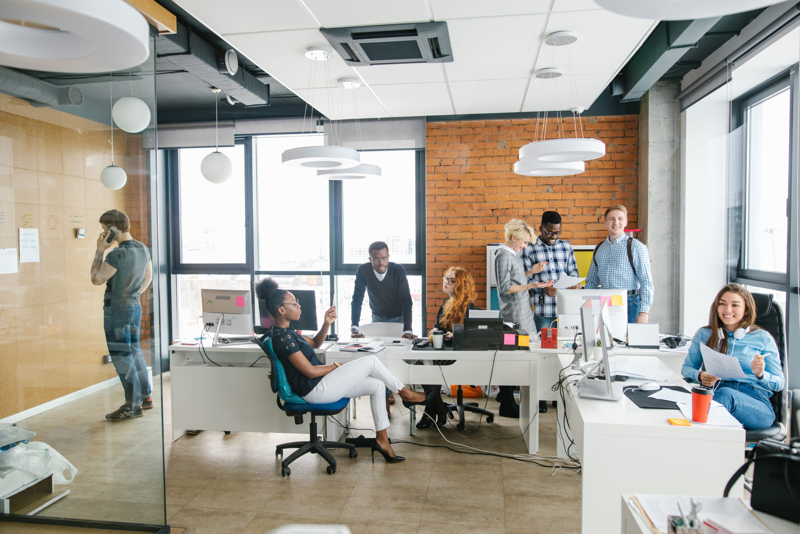 In einem modernen und offenen Büro sprechen verschiedenen Mitarbeitende miteinander und nutzen die Design Thinking Methode