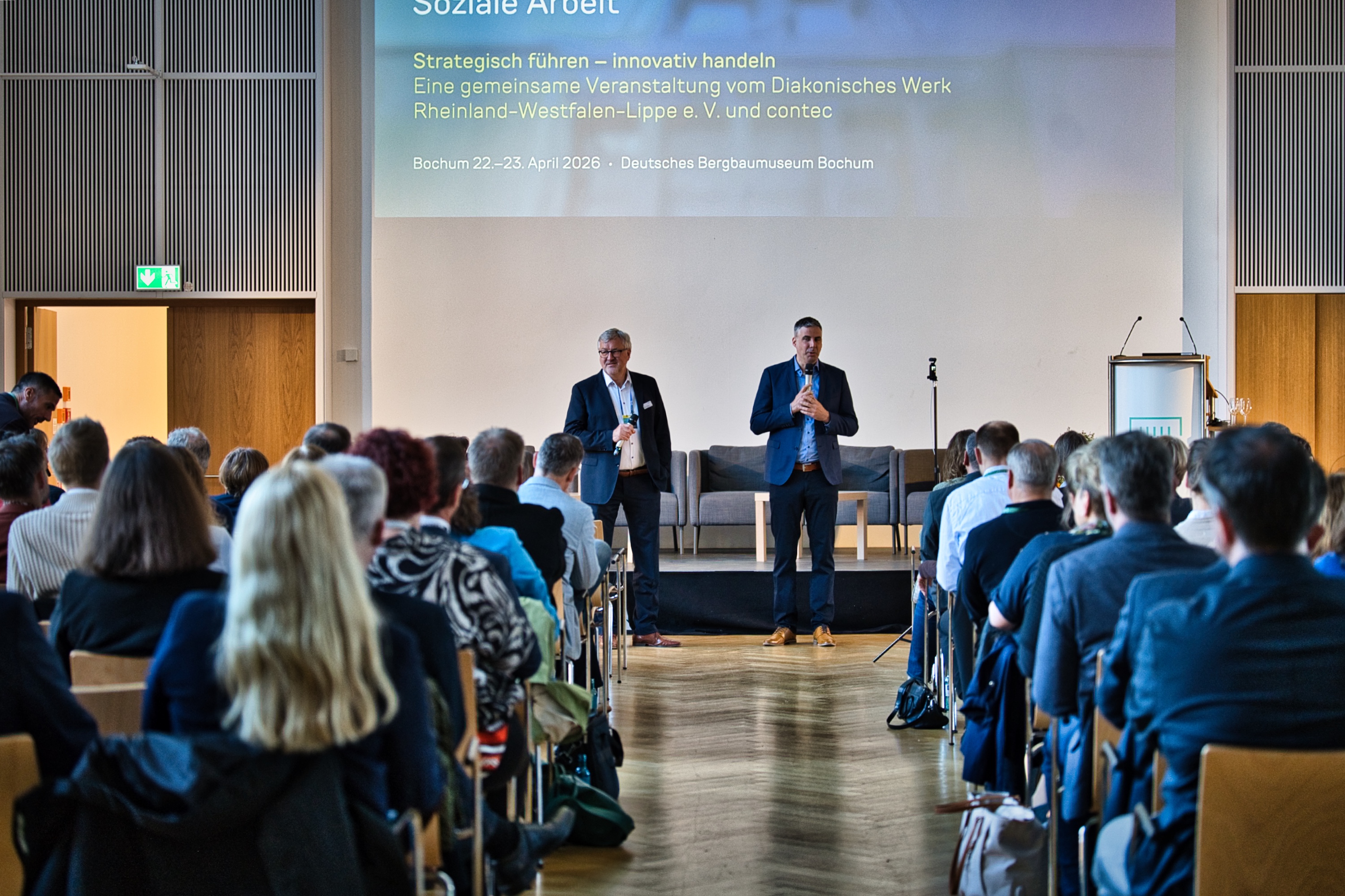 Personalkongress contec und Diakonie RWL: Einblick in das Auditorium, vorne stehen zwei Redner