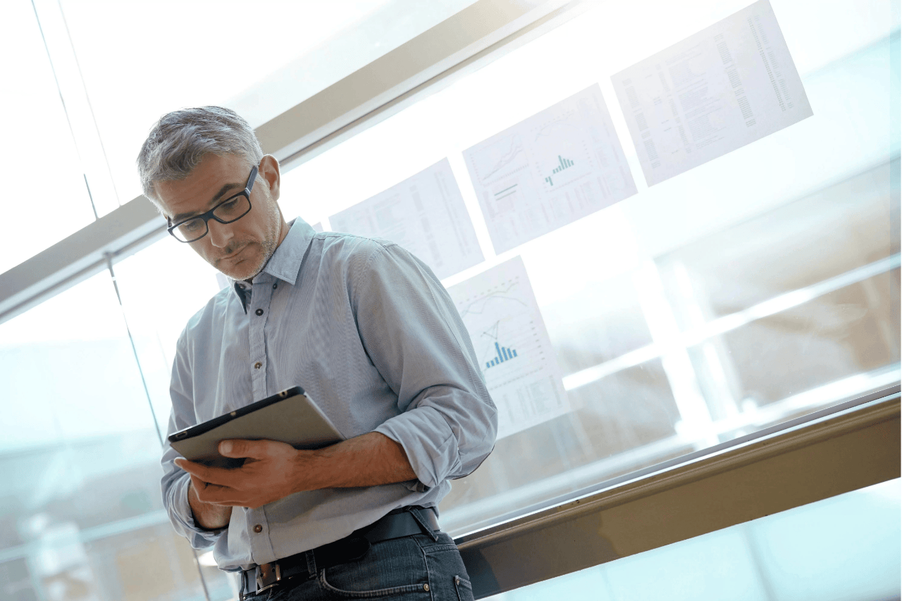 Geschäftsmann beim Analysieren von Ergebnistabellen, die am Bürofenster hängen