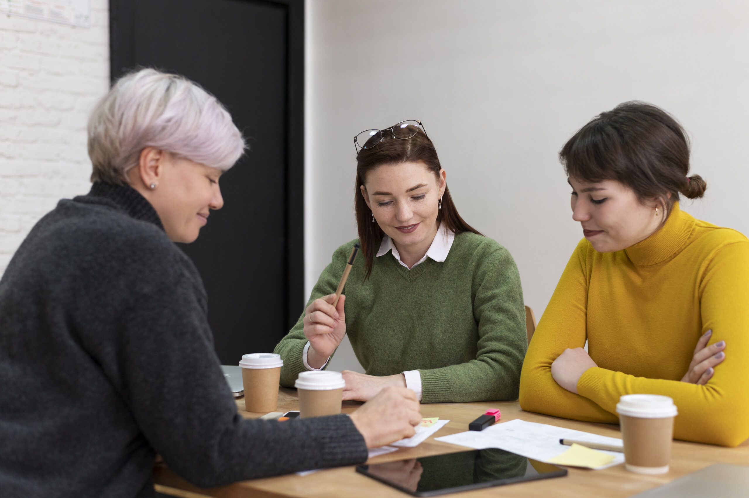 Drei Mitarbeiterinnen sitzen an einem Tisch und arbeiten zusammmen_Dienstpläne in der Eingliederungshilfe