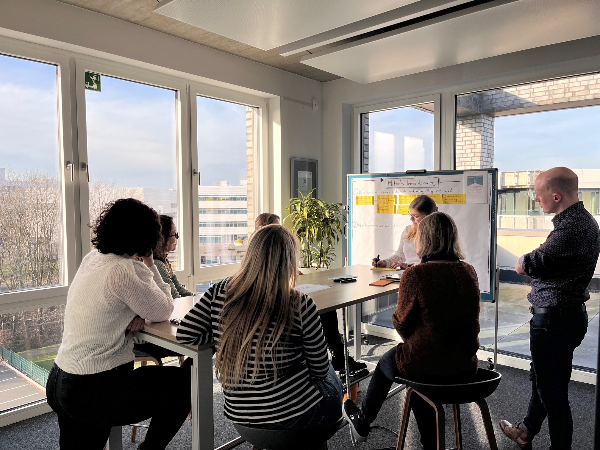 Menschen, die an einem Stehtisch im Bochumer Büro der contec GmbH im Rahmen des World Café miteinander diskutieren.