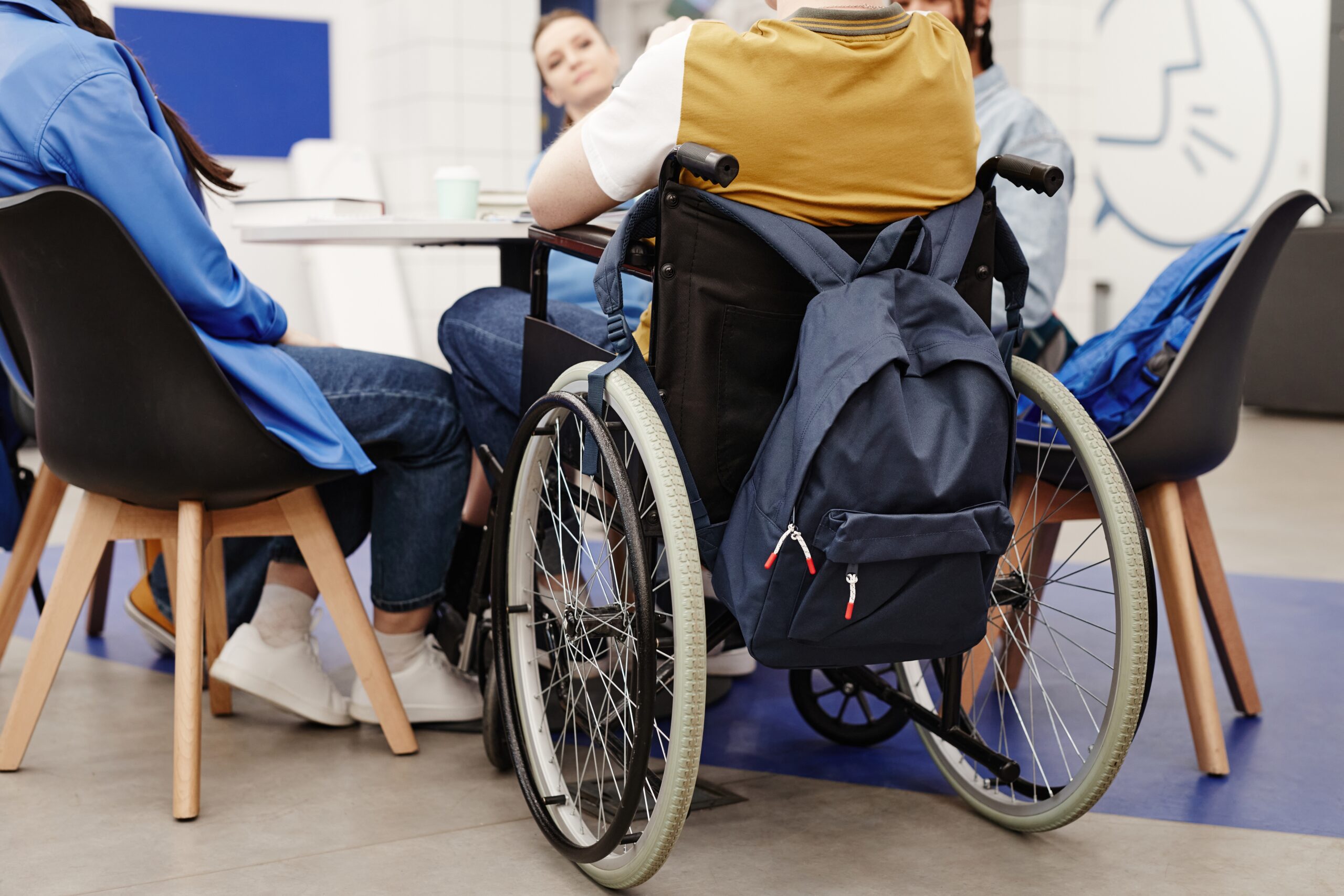 Mehrere Personen sitzen an einem Tisch, darunter ein Mann im Rollstuhl