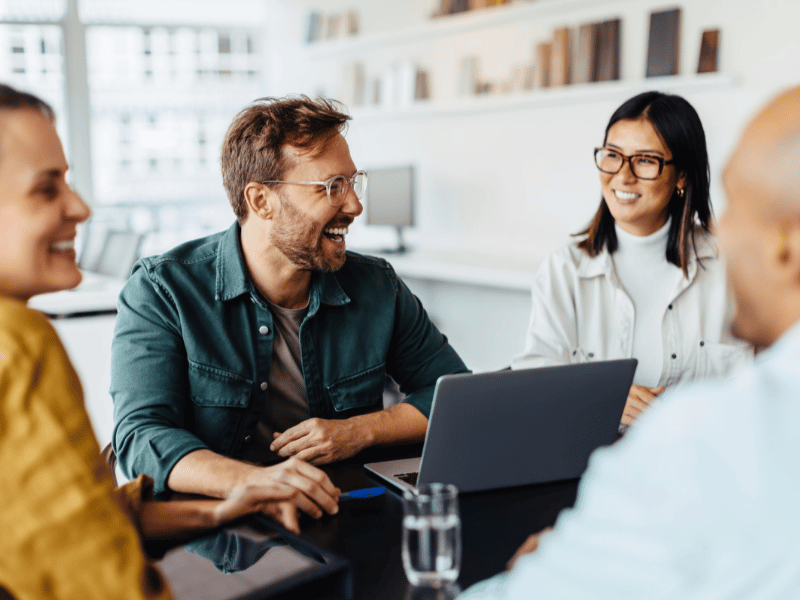 Arbeitskollegen lachen und arbeiten zusammen.